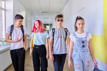 Group of teenage students walking together along school corridor
