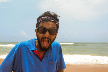 portrait of young indian man on baga beach, goa