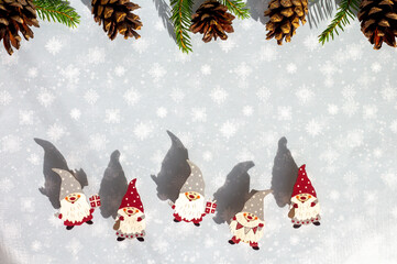 a frame of little wooden scandinavian gnomes and pine cones, christmas card with snowy background and cute elves in red and grey hats, copy space