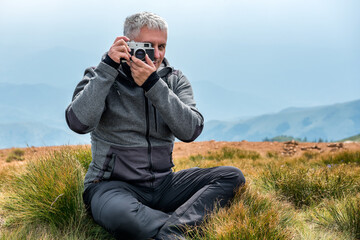 Photographer with old analog camera at a Mountain top. Mountain landscape view. Mountain layers landscape. Meadows and mountains landscape. Blue mountains layers landscape. Top of the Mountains