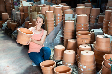 Young woman customer looking decorative clay pot for garden in the shop