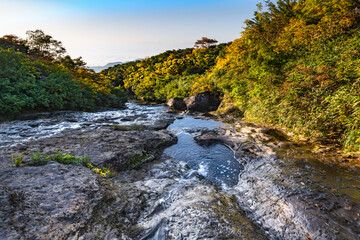 栗駒山紅葉の季節の渓流を横切る登山道と雲海