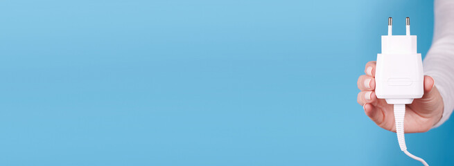Hand with white power supply unit. Isolated on blue background, copy space template, banner.