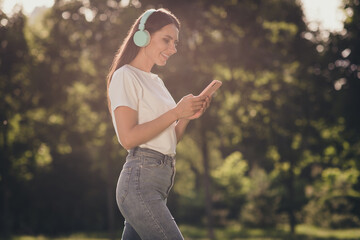 Profile side view portrait of her she nice attractive pretty cheerful cheery thin girl going enjoying listening single stereo sound playlist hit chatting blogging sunny day fresh air