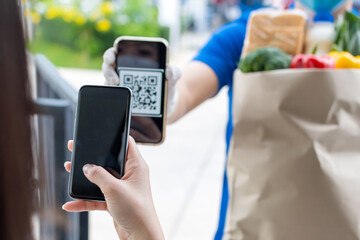 customer hand using digital mobile phone scan QR code paying for buying fresh food set bag from food delivery service man, express delivery, digital payment technology and fast food delivery concept