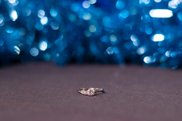 an engagement ring near blue shiny tinsel for christmas tree. new years proposal theme