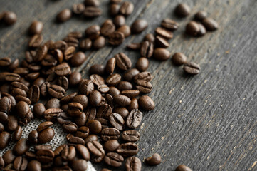 Coffee beans on a linen textile and on a wooden table background. Fresh arabica coffee beans.