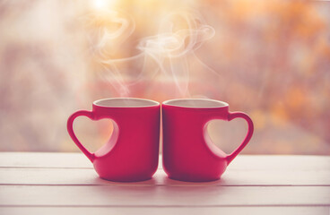 two heart shaped mugs with tea on natural background