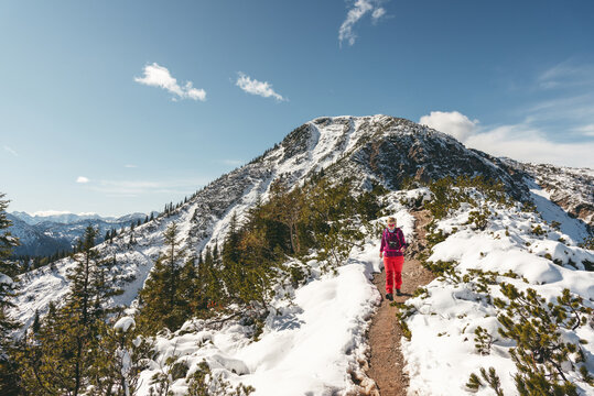 Wanderin im Neuschnee auf dem Gratweg zwischen Heimgarten und Herzogstand mit Heimgarten-Gipfel im Hintergrund