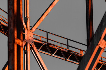 Old gas structure in dangerous area. Details of joints and rivets under a warm sunset, orange...