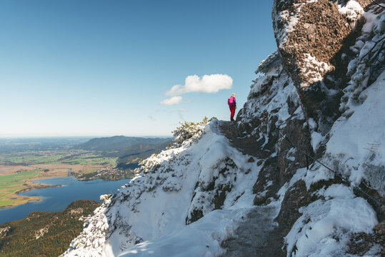 Wanderin im Neuschnee auf dem Gratweg zwischen Heimgarten und Herzogstand mit Blick auf den Kochelsee