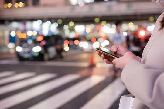 夜の渋谷でスマホを操作する若い女性の手元