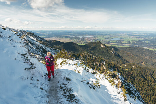 Wanderin im Neuschnee auf dem Gratweg zwischen Heimgarten und Herzogstand mit Blick ins Alpenvorland