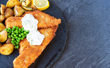 Fish and chips with peas on dark background table