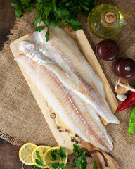Cod fillet. Raw cod fillet on a chopping board on a brown kitchen table. Preparation for cooking fish. Top view	