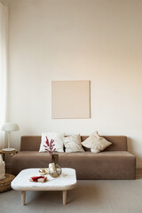 Comfortable modern interior design concept. Sofa, coffee table with decorations, lamp, blank picture frame on the wall.