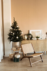 Modern home interior design concept. Comfortable cozy living room decorated with Christmas tree with gifts, rattan chair. Christmas / New Year celebration decorations.