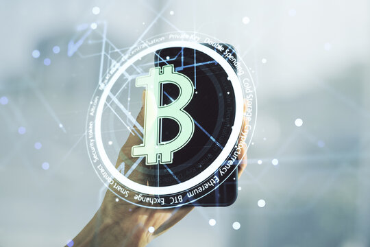 Double exposure of creative Bitcoin symbol and hand with cell phone on background. Cryptocurrency concept