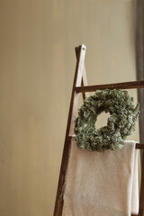 Round homemade wreath frame made of fir needles. Minimalist modern interior design. Christmas celebration decoration.