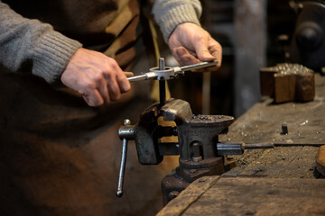 Professional blacksmith working with metal - quenching hot iron part with water at forge, workshop....