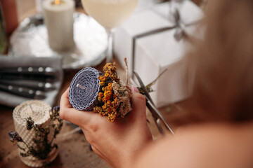 DIY wax candle making process. Woman making decorative wax candle and decorates with dried flowers, close-up of hands