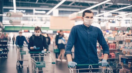 young man in a protective mask with a shopping cart