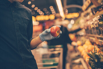 man in a protective mask when selecting apples at the supermarket.