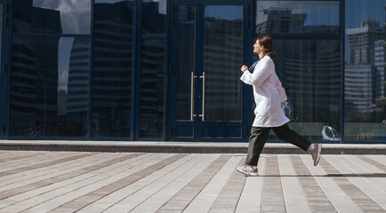 Fototapeta na wymiar woman doctor runs down a city street.