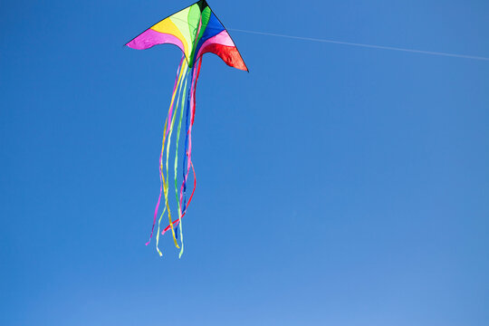 A colorful triangle kite flies under blue sky. sunny autumn.