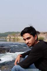 Young indian man sitting at river side