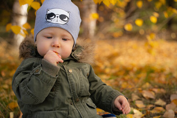 Small child eating bun outside on cold autumn day. A close-up of the face of a small boy with blue...