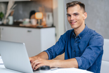 male freelancer works on a laptop in his kitchen.