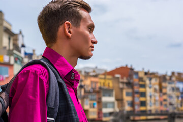 A young man with a backpack stands on the river bank Onyar in Girona, Spain