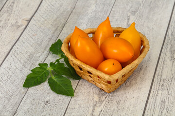 Yellow tomato heap in the wooden bowl