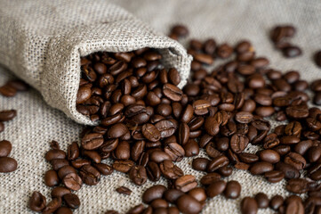 Coffee scattered from a linen bag. Fresh arabica coffee beans on linen textile.