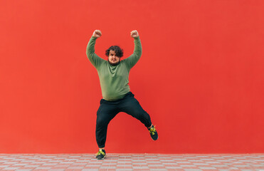 Positive fat dancer in casual clothes shows a performance on the street on a red background. Funny...