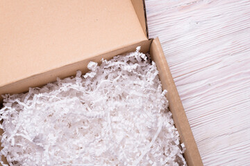 Shredded paper filler in cardboard box on wooden table