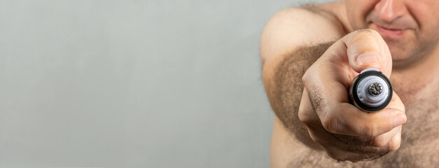 A man removes hair from his ear with a trimmer closeup