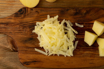 Raw Grated Potato on Wooden Cutting Board Background