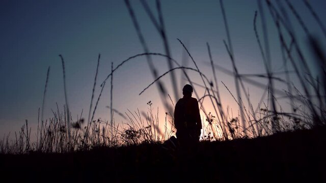 Man in a field falls on his knees on the background of sunset