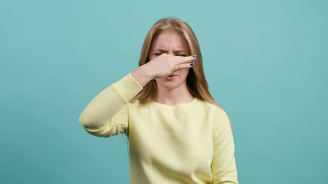 Close up of a girl that is showing disgust, pinching her nose to avoid bad smell. Negative emotions, nasty feelings.
