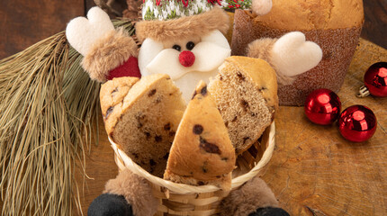 Sliced ​​panettone in a Santa Claus basket and Christmas balls on the rustic wooden table with black background, selective focus.