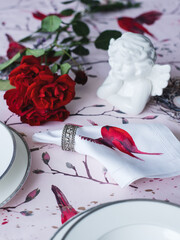 Table setting with a rose. Napkin with a bird and an angel on a bright tablecloth