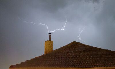 Thunderbolt Lightning strikes house chimney in a storm in the countryside