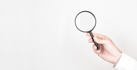 Man holds magnifying glass on wall background. Concept of search, recruitment and job search.