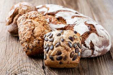 Gold rustic crusty loaves of bread and buns on wooden background. Still life captured from above top view, flat lay.