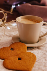 Cozy winter or autumn morning at home. Hot coffee, cookies warm blanket and garland, Swedish hygge concept.