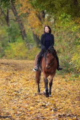 Foto op Canvas Equestrian woman ride horseback through autumn  golden foliage © horsemen
