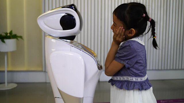 asian child extends a hand to the robot. concept of friendship between the robot and child