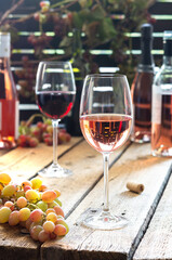 Glasses with red and rose wine, outdoor recreation, wooden table with glasses of wine, bottles of wine and grapes
